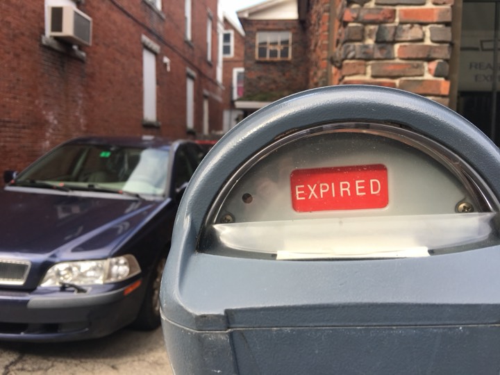 Close-up of a parking meter reading EXPIRED on a brick-lined street