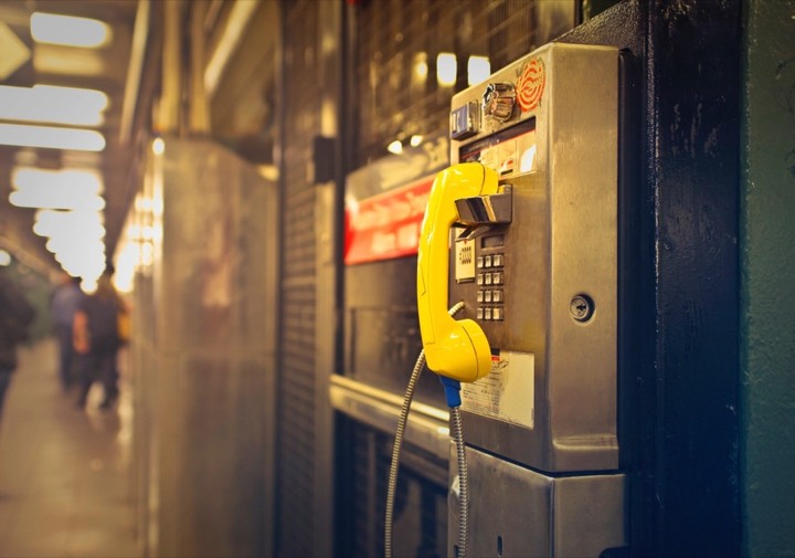 A payphone with a yellow handset on an underground station platform