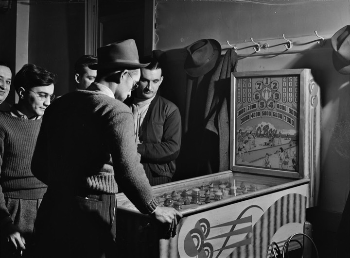 Men in hats gathered around a pinball machine at a steelworkers' club, 1941